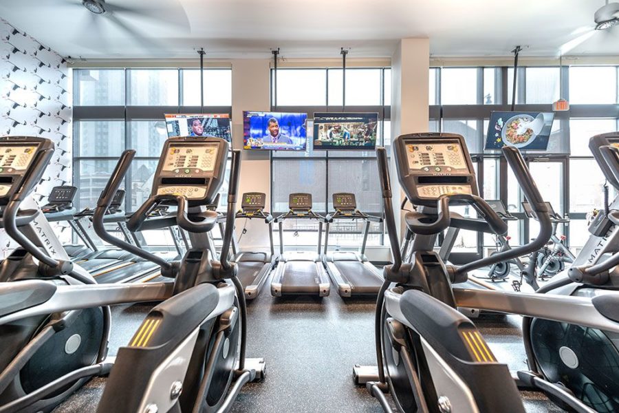 exercise room with ellipticals and treadmills at 212 east's students apartments